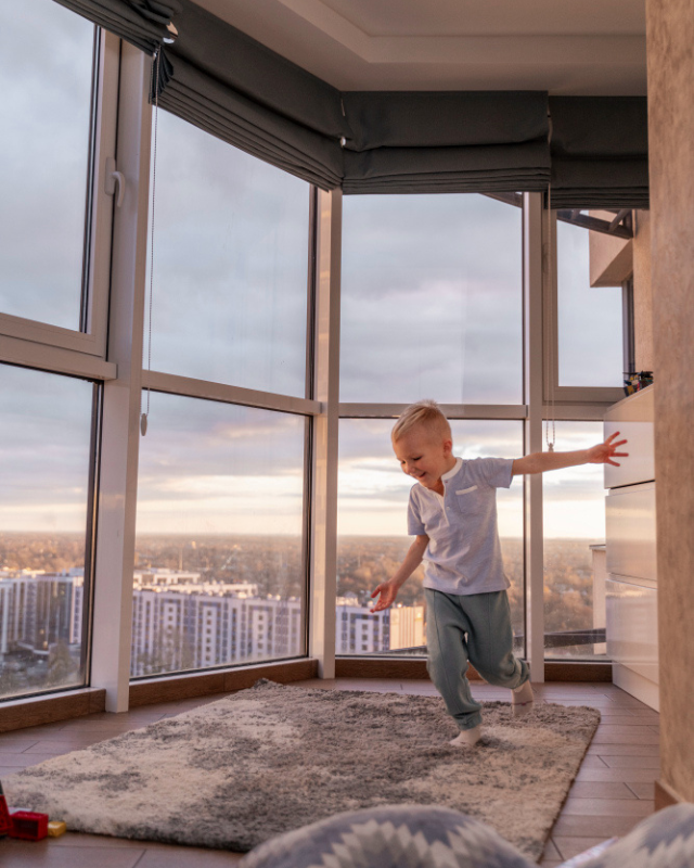 niño corriendo en interior con fondo de ventanal de aluminio